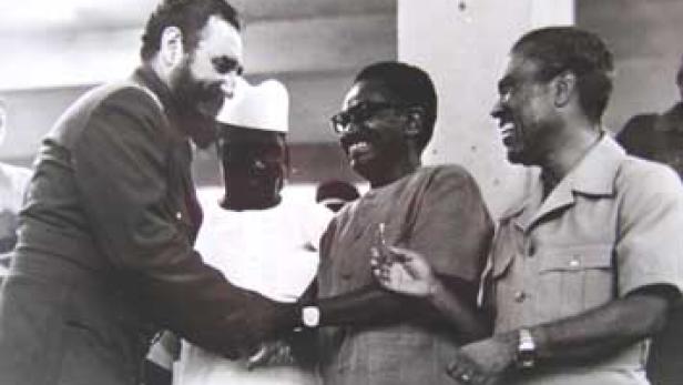 Fidel Castro schüttelt die Hand eines Mannes, umgeben von weiteren Personen.