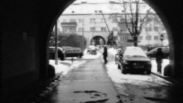 Ein verschneiter Durchgang mit Blick auf eine Straße und ein Gebäude im Hintergrund.