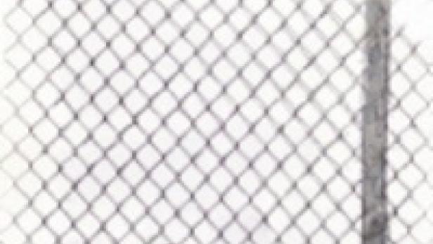 Eine Frau geht an einem Maschendrahtzaun entlang.