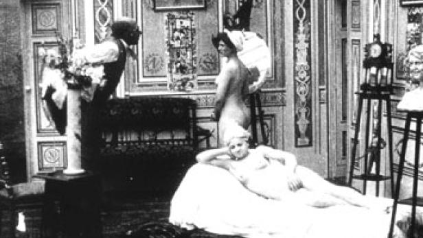 Eine Aktstudie mit zwei Frauen in einem Atelier, eine liegend, die andere stehend vor einer Staffelei.