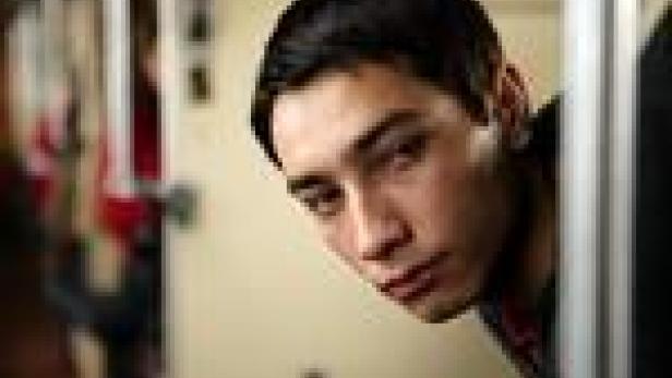 Ein junger Mann schaut aufmerksam aus dem Hintergrund.