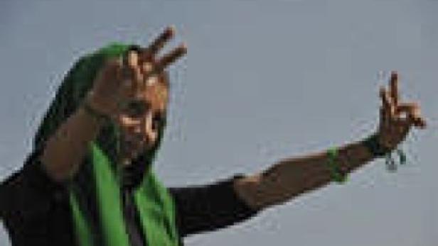 Eine Frau mit grünem Kopftuch zeigt das Victory-Zeichen.