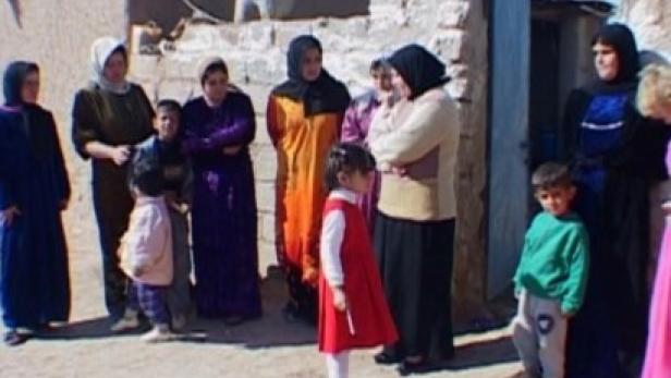 Eine Gruppe von Frauen und Kindern steht im Freien vor einem Gebäude.