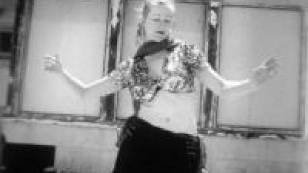 Eine Frau posiert vor einem alten Kino in der Wüste.