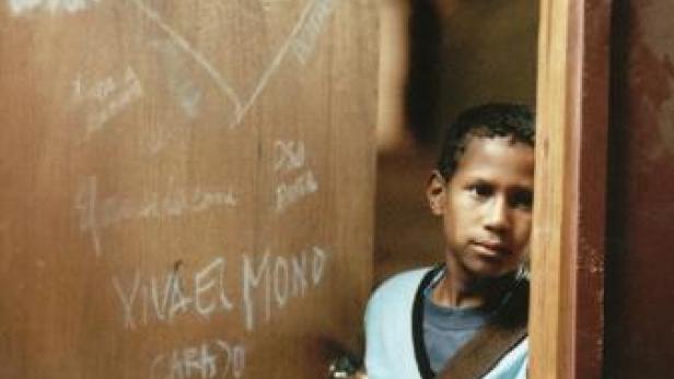 Ein junger, dunkelhäutiger Junge steht in einer Türöffnung.