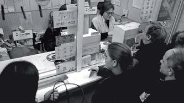 Eine Menschenschlange vor einem Schalter in einem Büro.