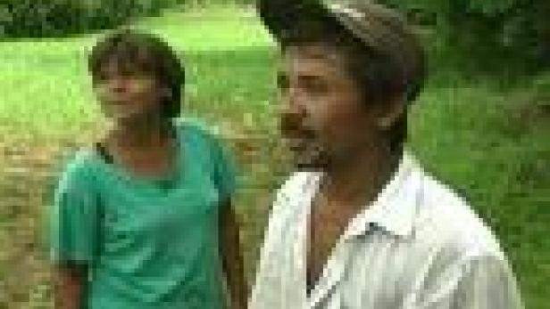 Ein Mann mit Mütze und eine Frau stehen auf einer grünen Wiese.