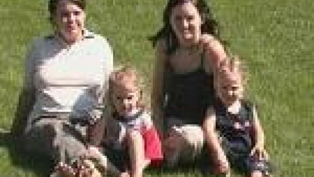 Zwei Frauen sitzen mit zwei kleinen Kindern auf einer Wiese.