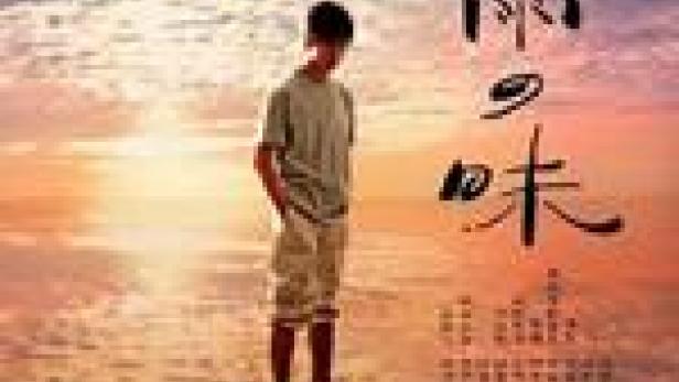 Ein junger Mann steht am Strand bei Sonnenuntergang. Im Vordergrund japanische Schriftzeichen.