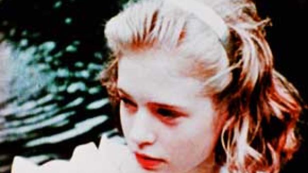 Eine junge Frau mit blonden Haaren und einem Haarband blickt nach links.