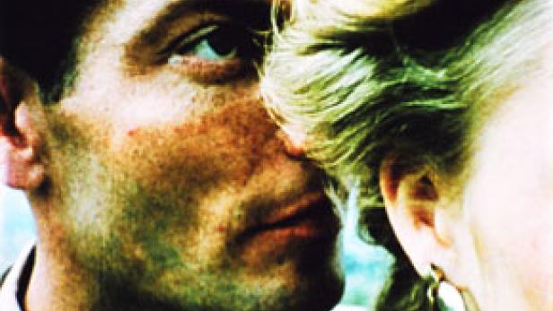 Ein Mann und eine Frau stehen einander sehr nah, fast Stirn an Stirn.