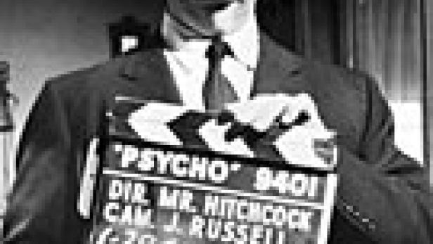 Alfred Hitchcock hält eine Filmklappe für den Film „Psycho“ in der Hand.
