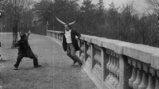 Ein Mann mit Flügeln wird von einem Jungen auf einem Gehweg gejagt.