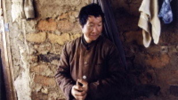 Ein Mann in einer einfachen Hütte mit Lehmwänden.