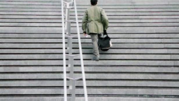 Ein Mann geht eine breite Treppe hinauf, neben ihm steht eine Leiter.