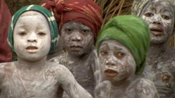 Eine Gruppe Kinder mit traditioneller Körperbemalung und bunten Kopfbedeckungen.