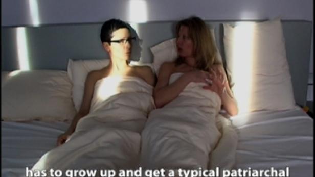 Zwei Frauen liegen nebeneinander in einem Bett, zugedeckt mit einer weißen Decke.