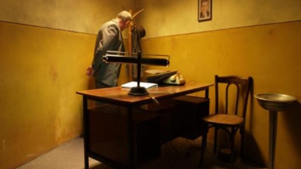 Ein Mann in einem Büro mit gelben Wänden beugt sich über einen Schreibtisch.