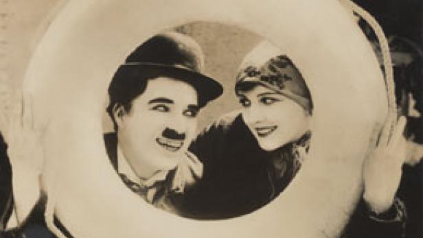 Charlie Chaplin und eine Frau blicken durch einen Rettungsring.