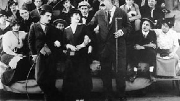 Eine Schwarzweißaufnahme von Charlie Chaplin mit Schauspielkollegen.