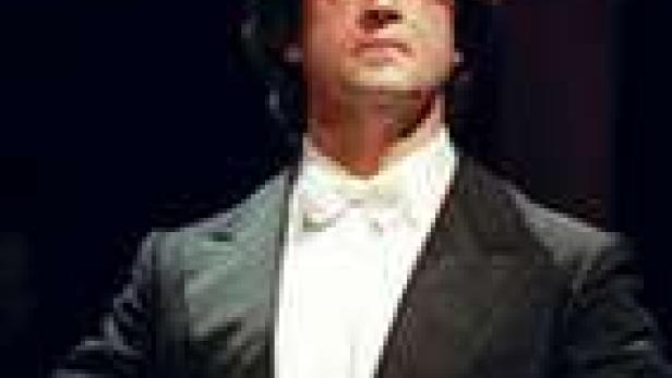 Ein Dirigent mit dunklen Haaren und einem weißen Hemd mit Fliege.