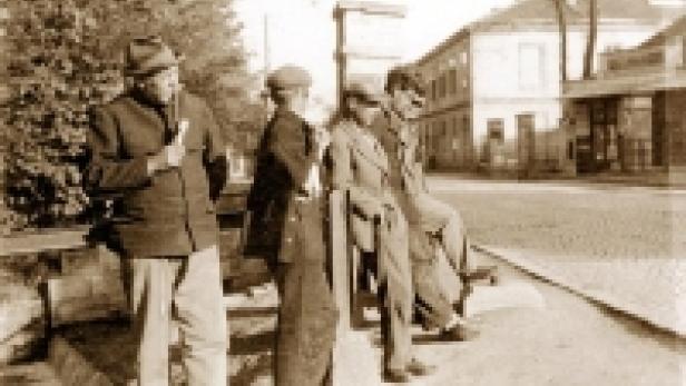 Eine Gruppe von Männern steht und sitzt an einer Straße in einer Stadt.