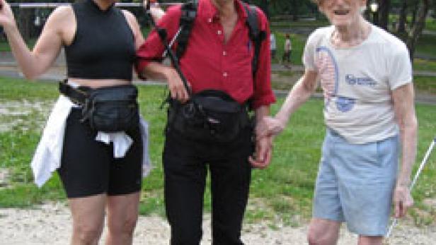 Drei Personen stehen im Freien, eine Frau, ein Mann und ein älterer Mann, alle mit Hüfttaschen.