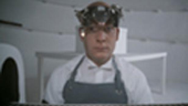 Ein Mann mit einer Apparatur auf dem Kopf schaut in die Kamera.