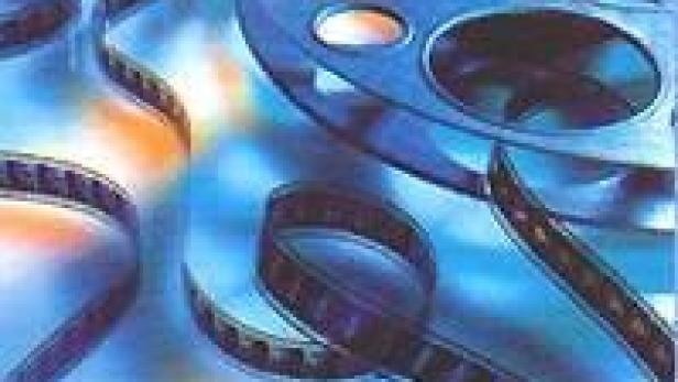 Mehrere Filmrollen liegen auf einem blauen Untergrund.