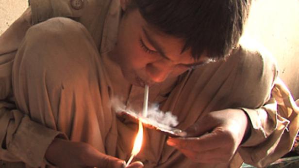 Ein Junge raucht eine Zigarette, während er ein Streichholz hält.