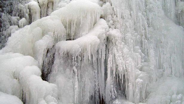 Ein zugefrorener Wasserfall mit dicken Eiszapfen.