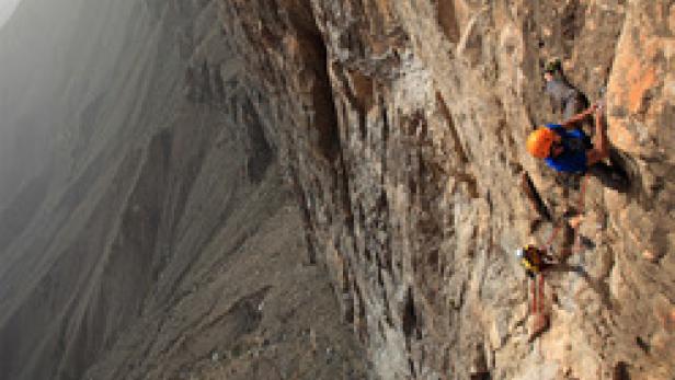 Zwei Kletterer an einer steilen Felswand.