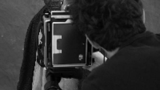 Ein Fotograf macht ein Porträt einer älteren Person mit einer Großformatkamera.