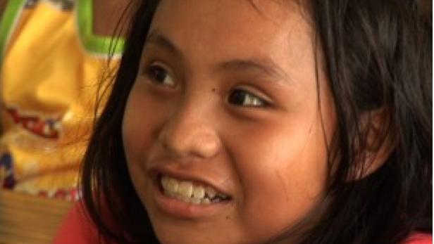 Ein junges Mädchen lächelt und schaut zur Seite.