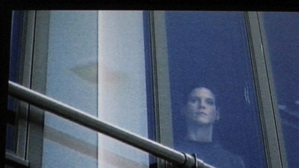 Eine Frau schaut aus einem Fenster in einem modernen Gebäude.