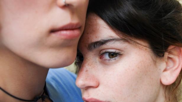 Zwei junge Frauen stehen eng beieinander.