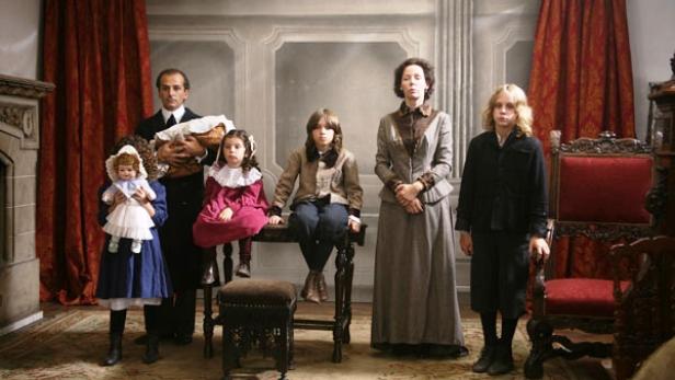 Eine formelle Familienaufnahme in historischer Kleidung in einem eleganten Raum.