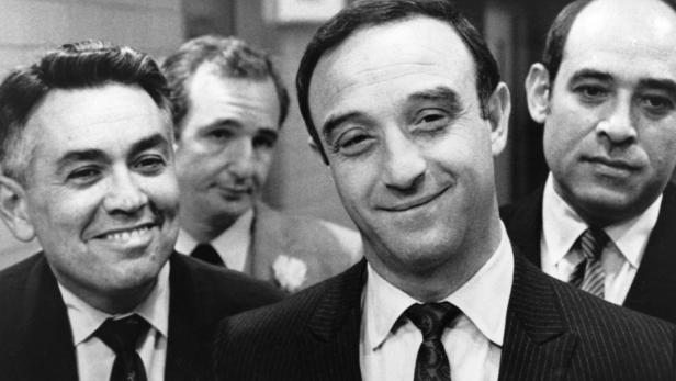 Eine Schwarzweißaufnahme von Peter Falk mit drei weiteren Männern.