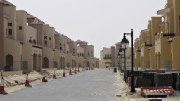 Eine Wohnstraße mit Häusern im mediterranen Stil und rot-weißen Leitkegeln.
