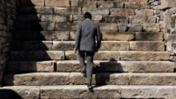 Ein Mann in einem Anzug steigt eine steinerne Treppe hinauf.
