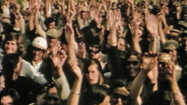 Eine große Menschenmenge jubelt mit erhobenen Händen.