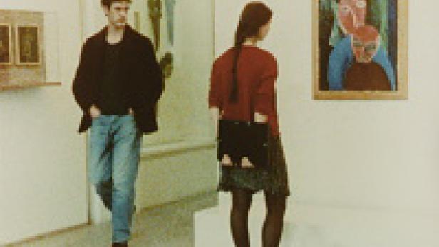 Ein Mann und eine Frau betrachten Gemälde in einer Kunstgalerie.