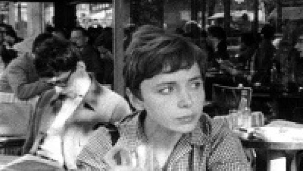Ein junger Mann sitzt in einem Straßencafé in Paris.