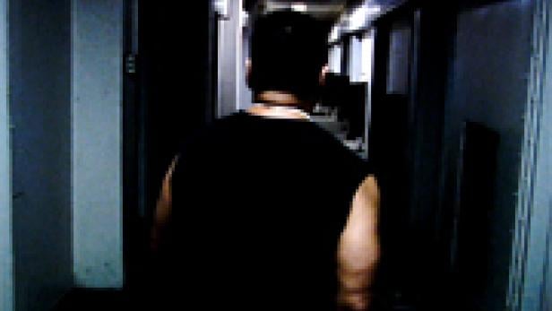 Ein Mann geht einen dunklen Korridor entlang.