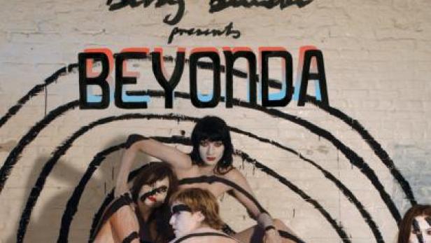 Eine Gruppe von Performerinnen posiert vor einer Wand mit der Aufschrift „BEYONDA“.