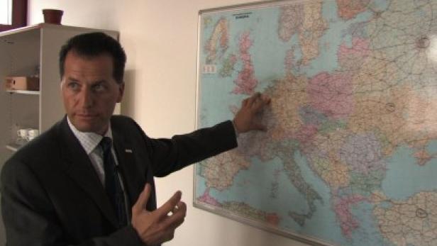 Ein Mann im Anzug zeigt auf eine Europakarte an der Wand.