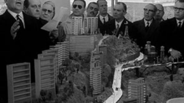 Eine Gruppe von Männern betrachtet ein Modell einer Stadtlandschaft.