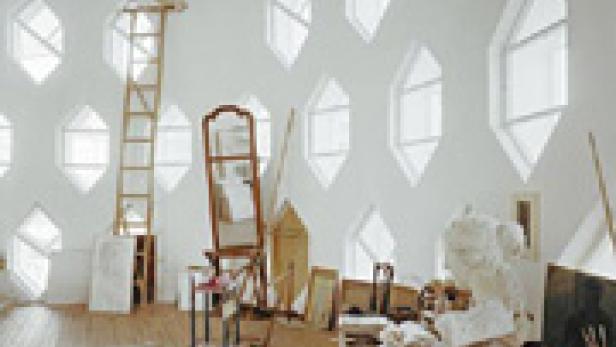 Ein Atelier mit vielen sechseckigen Fenstern, einer Leiter und diversen Kunstgegenständen.