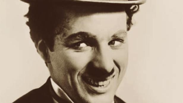 Ein Porträt von Charlie Chaplin mit Melone und einem verschmitzten Lächeln.