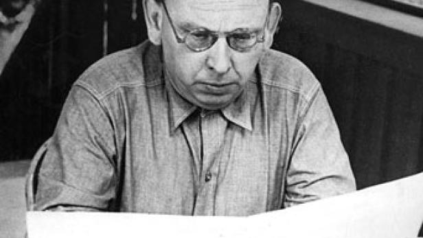 Ein Mann mit Brille liest ein großes Blatt Papier.